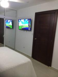 圣斐利-银港Habitación privada en Puerto Plata Bayardo的卧室配有一张床,墙上设有两台电视。