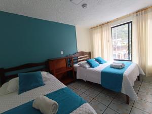 巴尼奥斯Hostal CañaLimeña的一间卧室设有两张带蓝色墙壁和窗户的床。