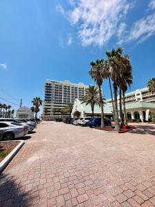 代托纳海滩Daytona Beach Resort Oceanfront CondoStudio的棕榈树停车场和大型建筑
