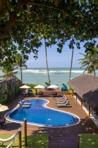 马塞约Flor de Lis Exclusive Hotel的海滩旁的游泳池配有椅子和遮阳伞