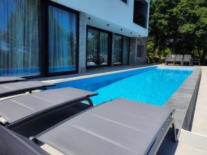 锡尼Villa Lapidea的一座房子旁的游泳池,配有两把躺椅