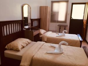 邦劳Tatay Seseng's Apartment的两个天鹅坐在一个房间里,睡在两张床上