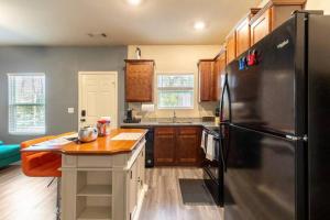亚特兰大Modern Retreat near Hartsfield-Jackson Airport的厨房配有黑色冰箱和木制橱柜。