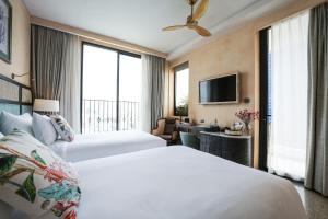 归仁L'amor Boutique Hotel Quy Nhơn的一间酒店客房,设有两张床和电视