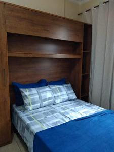 尼泰罗伊Loft Aconchegante no Centro de Niterói!!的一张带木制床头板和蓝色床单及枕头的床