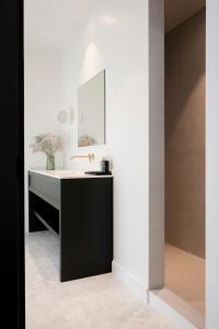 德哈恩Hotel des Brasseurs的浴室设有黑白水槽和镜子