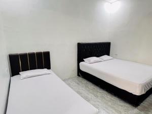 BinjaiRedDoorz Syariah @ Binjai Timur的两张睡床彼此相邻,位于一个房间里