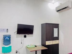BinjaiRedDoorz Syariah @ Binjai Timur的一间墙上配有电视和一张桌子的房间