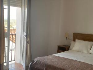 阿兰赫El Balcón de Alange的一间卧室设有一张床和一个滑动玻璃门