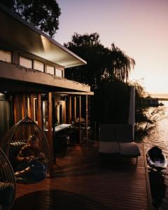 White SandsArk-imedes - Unique float home on the Murray River的坐在水边房子甲板上的男人