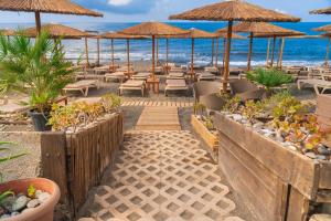 依拉佩特拉Tylissos Beach Hotel - Adults Only的海滩上的餐厅,配有椅子和遮阳伞