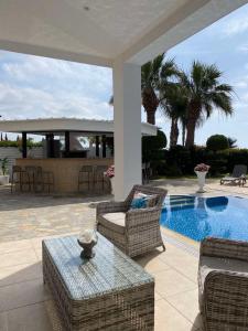 阿依纳帕Ionion Beachfront Villa的一个带桌椅的庭院和一个游泳池