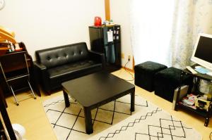 泉佐野MINPAKU-P 民泊p的客厅配有黑色真皮沙发和咖啡桌