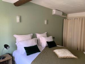艾格-莫尔特La flemme en rose的卧室配有一张带黑色枕头的大型白色床。