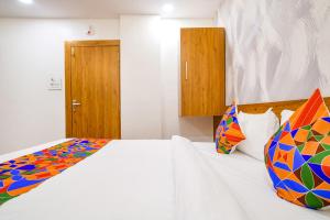 印多尔FabHotel Woodlark Inn的卧室配有白色的床和色彩缤纷的枕头