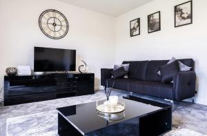 赫尔Beautiful Home in Kingston-Upon-Hull的客厅配有黑色沙发和时钟