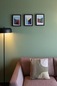 弗利辛恩Aparthotel Timmerfabriek Apartments I Kloeg Collection的一张带枕头的沙发,墙上有三张照片