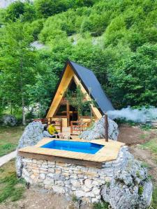 ŠavnikEtno apartmani Komarnica的一座小房子,在岩石上设有游泳池