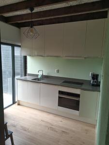 ErmUitrusthuisje的厨房铺有木地板,配有白色橱柜。