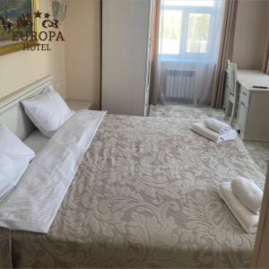 乌拉尔斯克Europa Hotel的一间卧室配有一张大床和两条毛巾