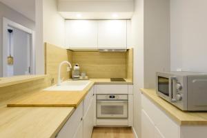 穆尔西亚Apartamento Suite Gran Vía的厨房配有白色橱柜、水槽和微波炉