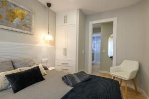 穆尔西亚Apartamento Suite Gran Vía的一间卧室配有一张床和一张白色椅子