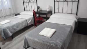 蓬特德乌梅Hostal San Cristobal - Pontedeume的一间卧室配有两张床和一张桌子及椅子