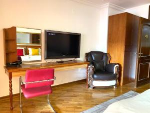 普里什蒂纳Urban Boutique Hotel的配有电视、两把椅子和一张床的房间