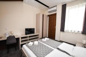 克拉多沃Atrijum Apartments and Rooms的酒店客房配有一张床、一张书桌和一台电视。