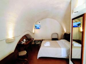 马泰拉Cave Rooms Sassi的一间卧室配有一张床、一张书桌和一面镜子