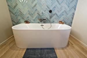 Les Petits Sablens的浴室设有白色浴缸,浴室设有瓷砖墙