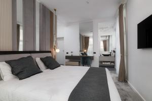 那沃达利Peninsula Luxury & Spa的卧室配有一张白色大床和一张书桌