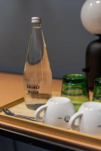 萨格勒布Stay Swanky Bed & Breakfast的一瓶水和桌子上的杯子