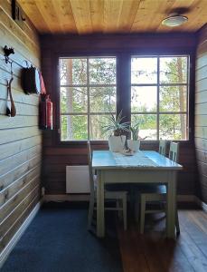 TuorilaNikolain tupa, vanha hirsitalo的一间带桌子和一些窗户的用餐室