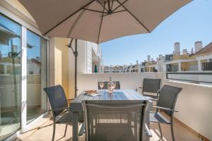 卡巴纳斯·德·塔维拉Delightful Cabanas 2 Bedroom apartment的阳台配有桌椅和遮阳伞