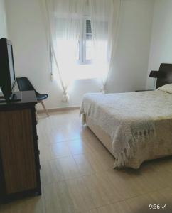滨海罗克塔斯Aguadulce Normandos的一间卧室配有一张床、一台电视和一个窗口