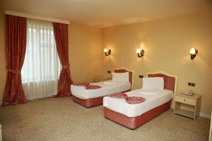 甘贾Deluxe Hotel Ganja的配有红色窗帘的酒店客房的两张床