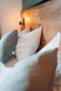 新锡德勒湖畔普巴赫Pur-INN das Gästehaus的一张带白色枕头和木制床头板的床