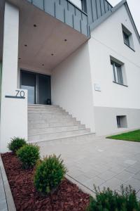 新锡德勒湖畔普巴赫Pur-INN das Gästehaus的前面有楼梯的白色建筑