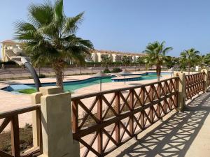 阿莱曼فيلا مميزه جدا في الساحل الشمالي ستيلا هايتس Stella Heights - Sidi Abd El-Rahman villa type M的木栅栏,设有两个棕榈树游泳池