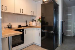 切霍齐内克Apartament Lawenda的厨房配有白色橱柜和黑色冰箱。