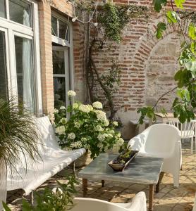 Penne-dʼAgenais苏拉宫住宿加早餐旅馆的庭院配有两把白色椅子和桌子,种有鲜花