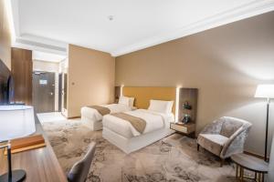 巴士拉Grand Millennium Al Seef Basra的酒店客房,配有两张床和椅子