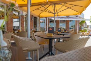 赫劳Oer't Hout的户外餐厅设有桌椅和黄伞