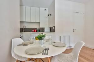 巴黎Studio - Appartement Quartier Montparnasse 2的白色的桌子、白色的椅子和白色的厨房