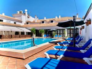 奥尔维拉Hotel Tugasa Sierra y Cal的一个带蓝色躺椅的游泳池和一间酒店