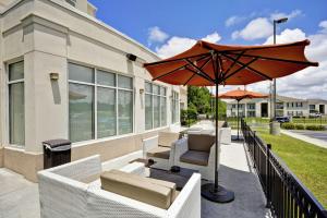 格尔夫波特格尔夫波特希尔顿花园酒店比洛克西机场店的庭院配有白色的椅子和遮阳伞。