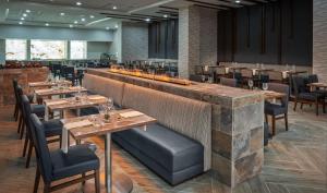 休斯顿休斯顿北希尔顿酒店的一间带木桌椅的餐厅和一间酒吧