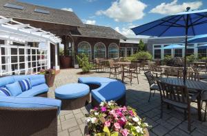 海恩尼斯海恩尼斯鳕鱼角希尔顿逸林酒店的庭院配有桌椅和遮阳伞。