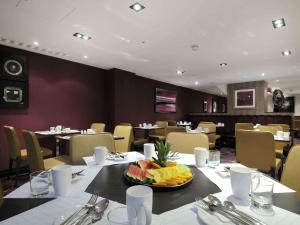 伦敦伦敦西区希尔顿逸林酒店的餐厅设有一张桌子,上面放着一碗水果